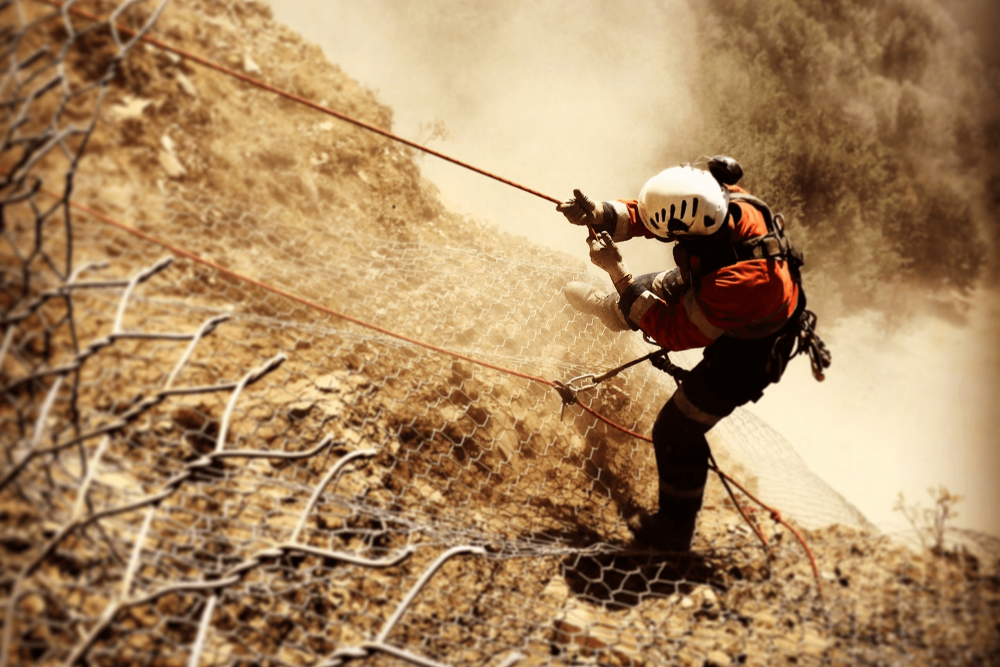 Rockfall mitigation expert on side of cliff.